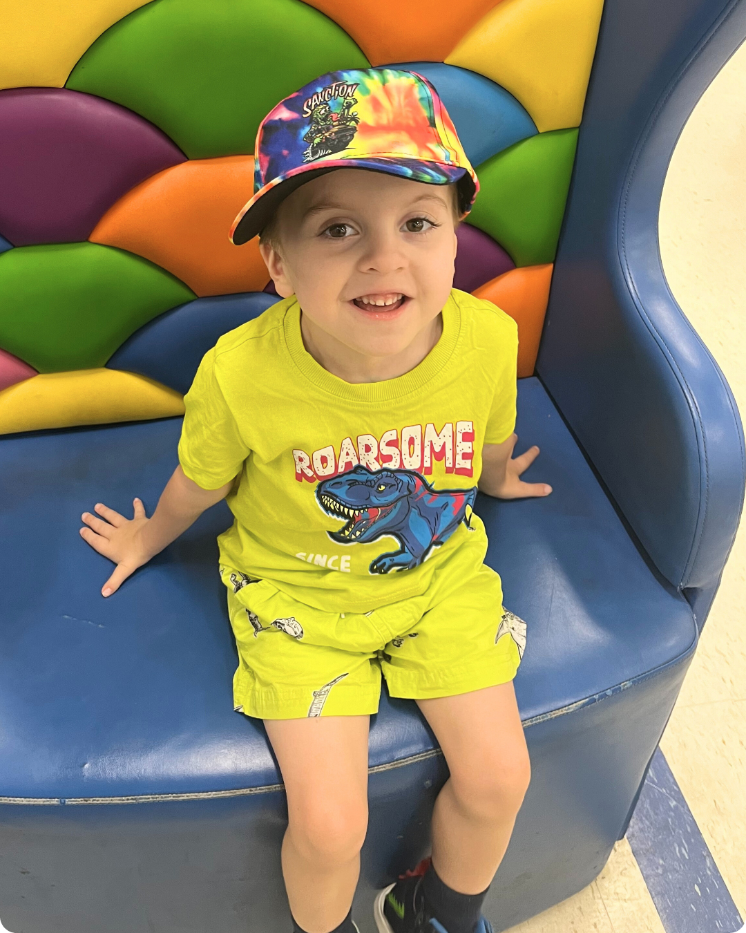 Young child looking to camera and smiling, wearing a bright coloured outfit.