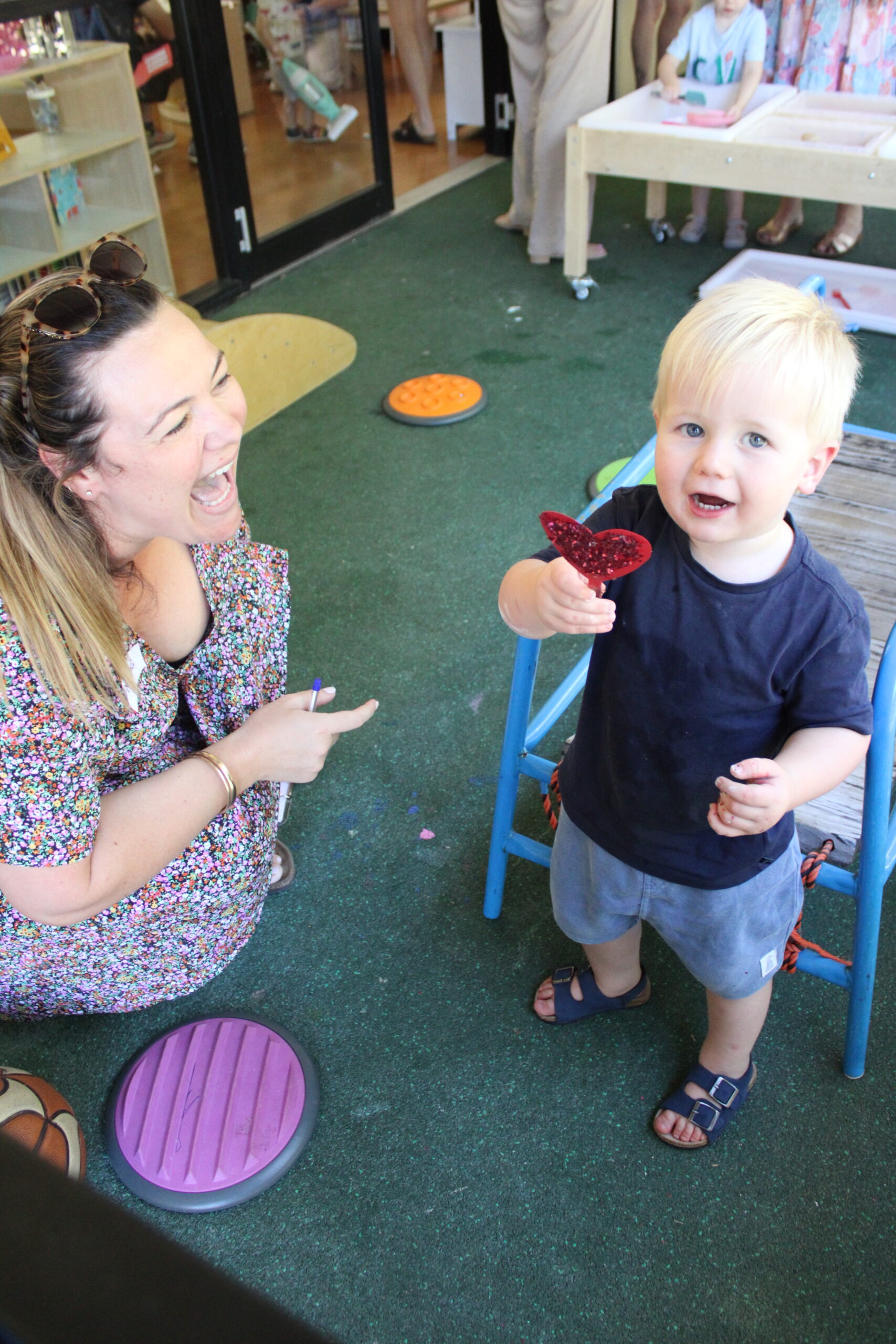 child smiling to camera and holding a small red love heart
