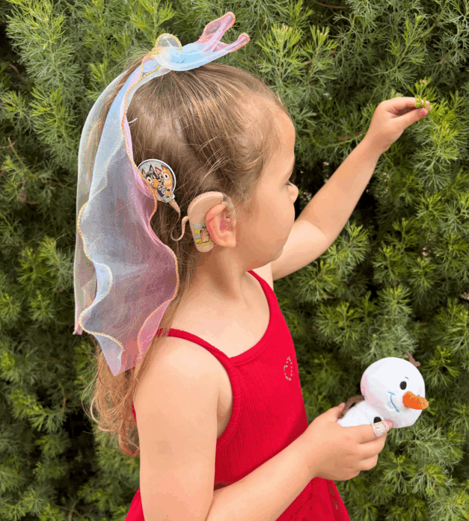 Child inn a red dress looking at a christmas tree