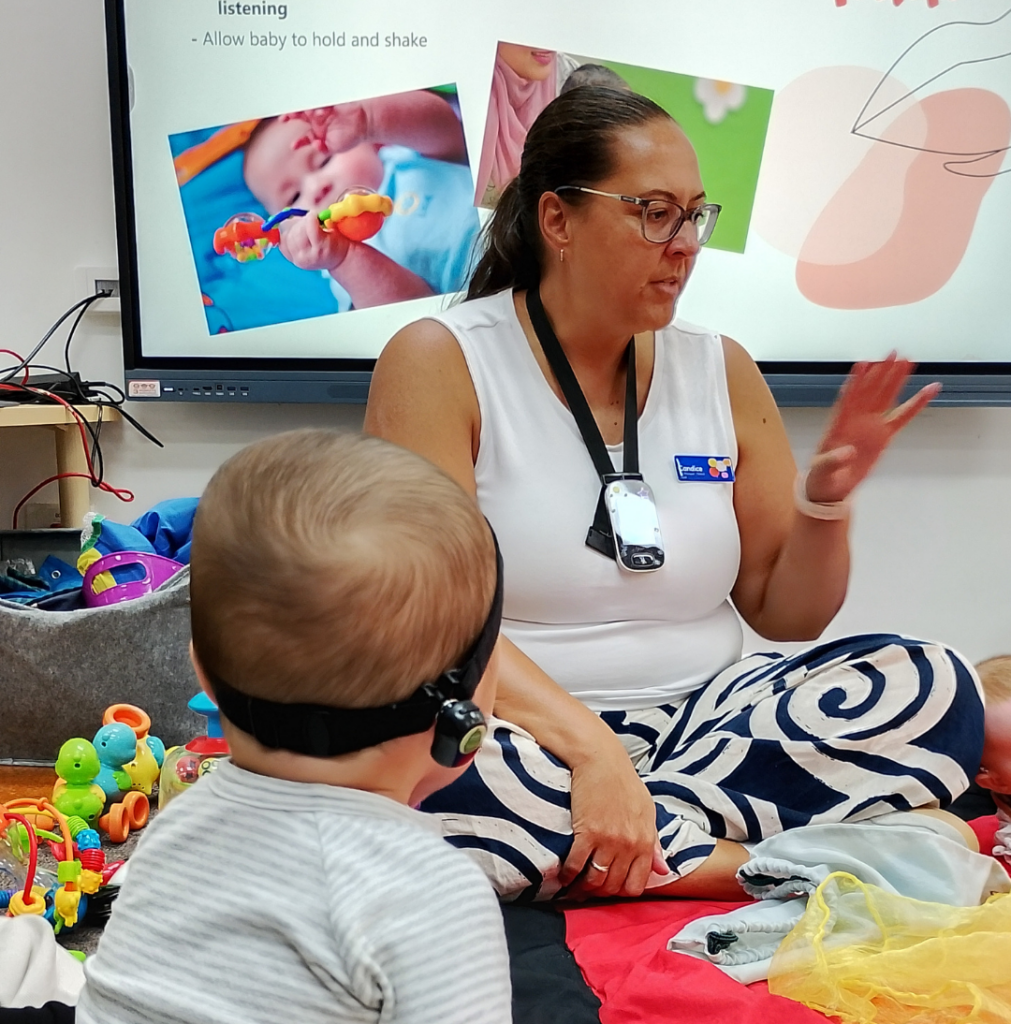 Young baby wearing a hearing device looking at a therapist during playgroup session