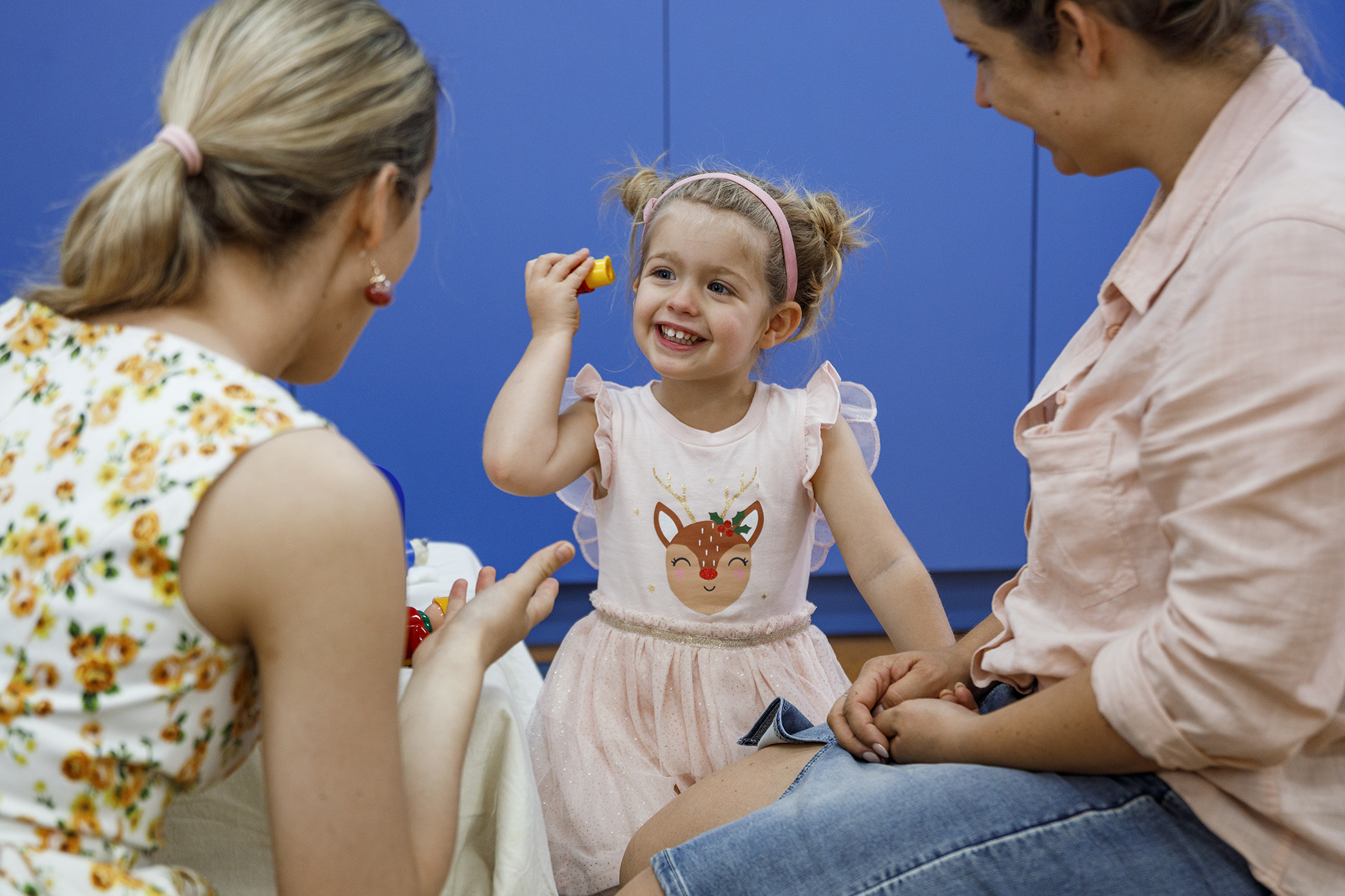 Young child holding a toy up to her ear