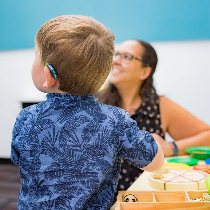 Young child wearing a hearing aid working with a therapist