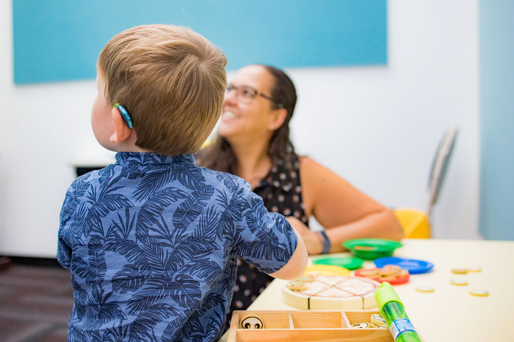 Young child wearing a hearing aid working with a therapist